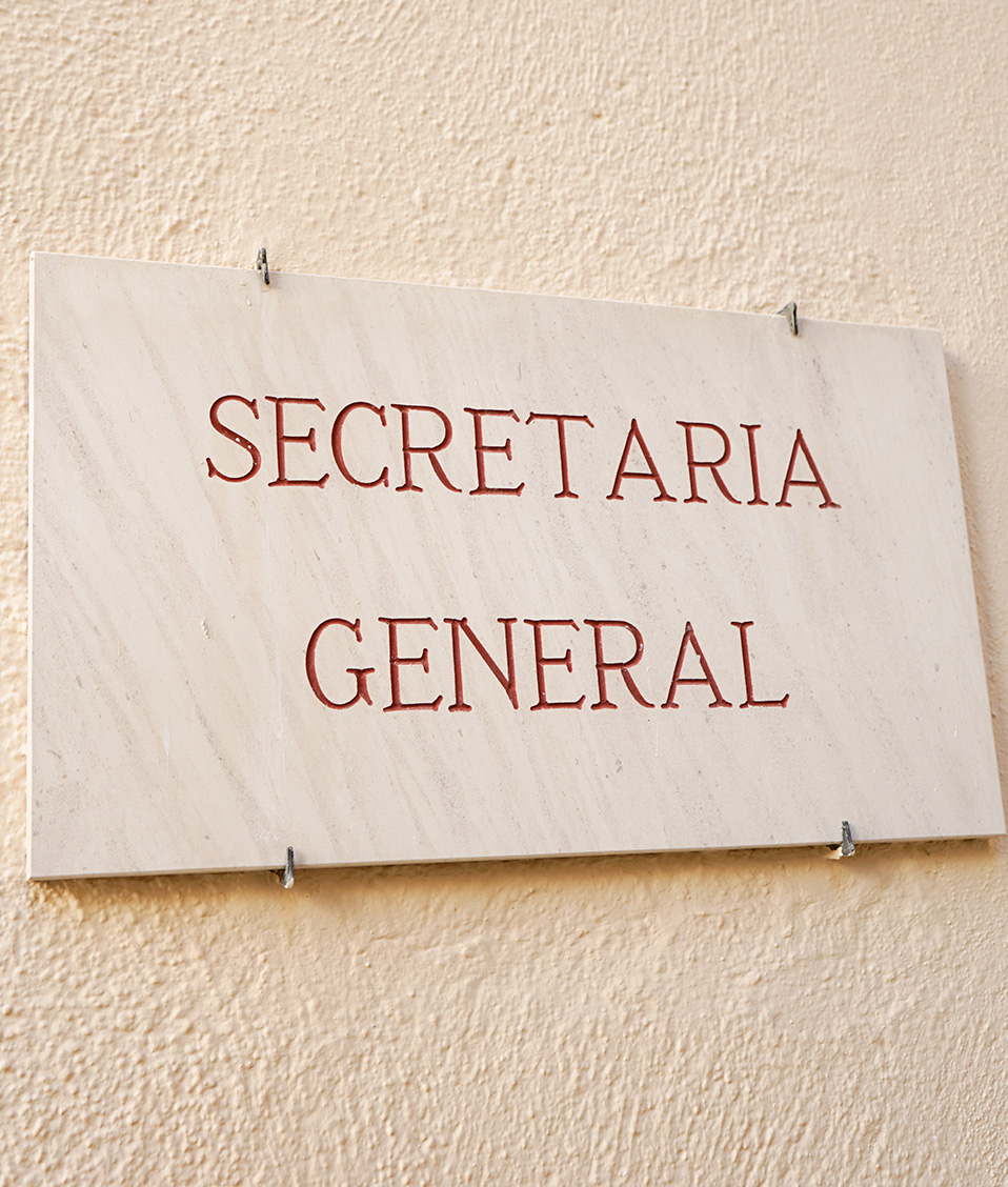 Cartel de mármol, en pared de patio del Hospital Real, indicando el acceso a Secretaría General de la Universidad de Granada
