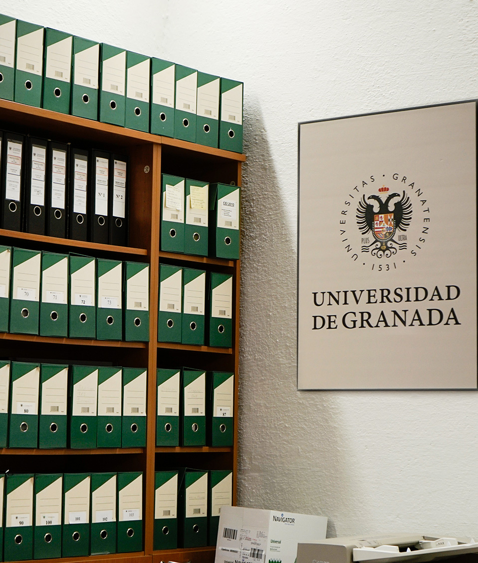 oficina con archivadores y cartel con logotipo de la Universidad de Granada en Hospital Real