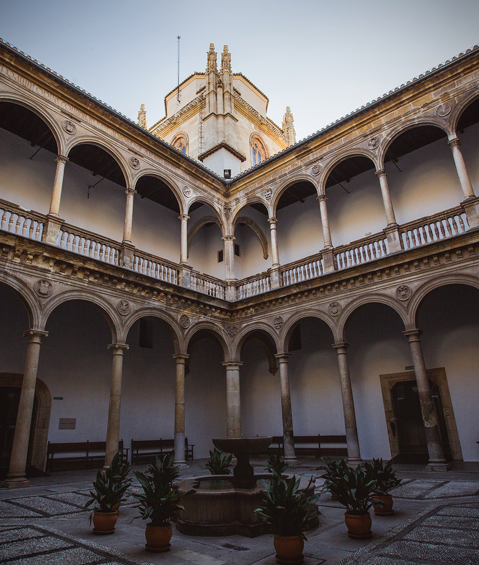 Vista desde abajo de uno de los patios del Hospital Real donde se ven los arcos del pasillo superior y la torre